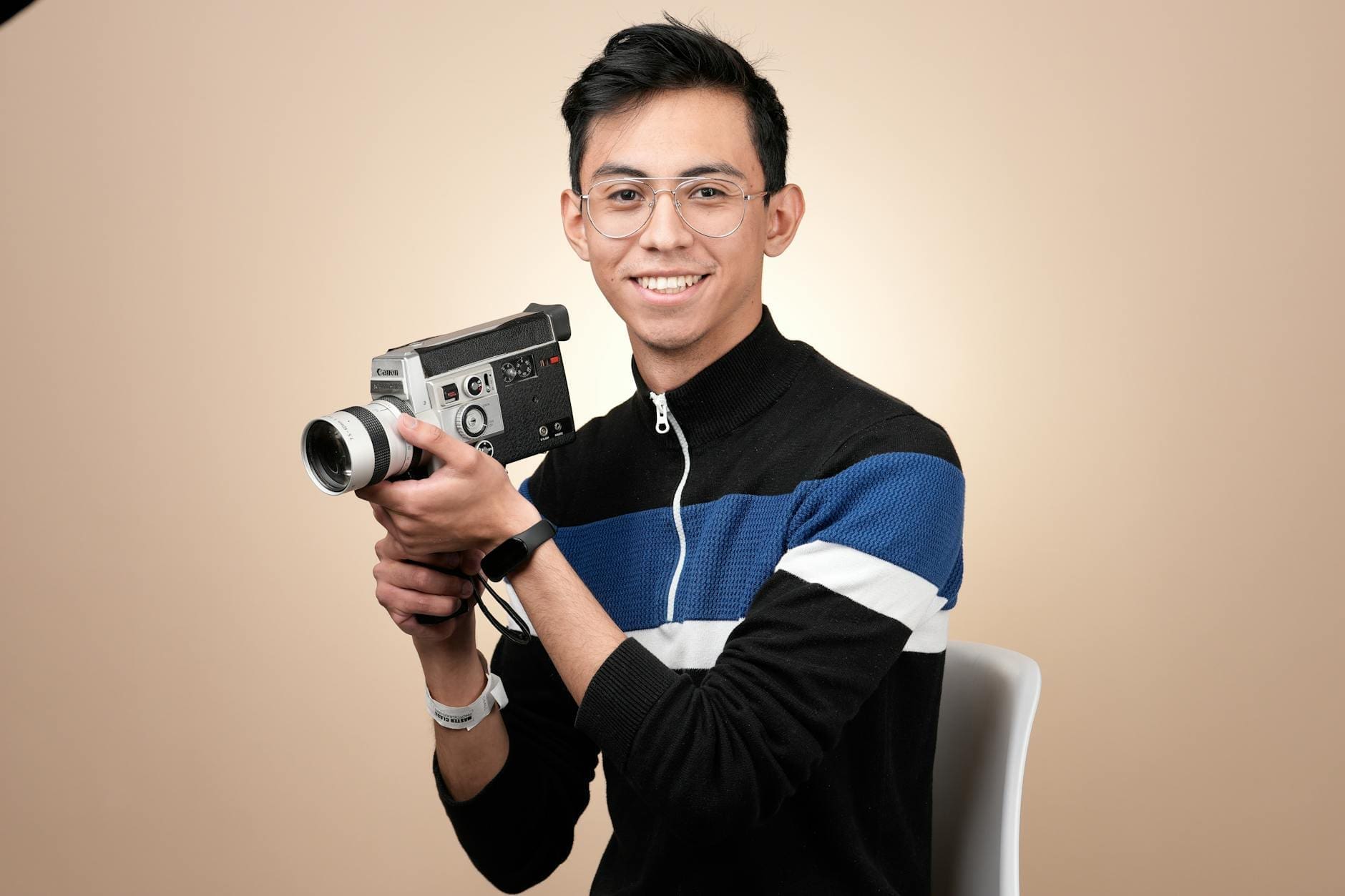 smiling man holding vintage movie camera in studio