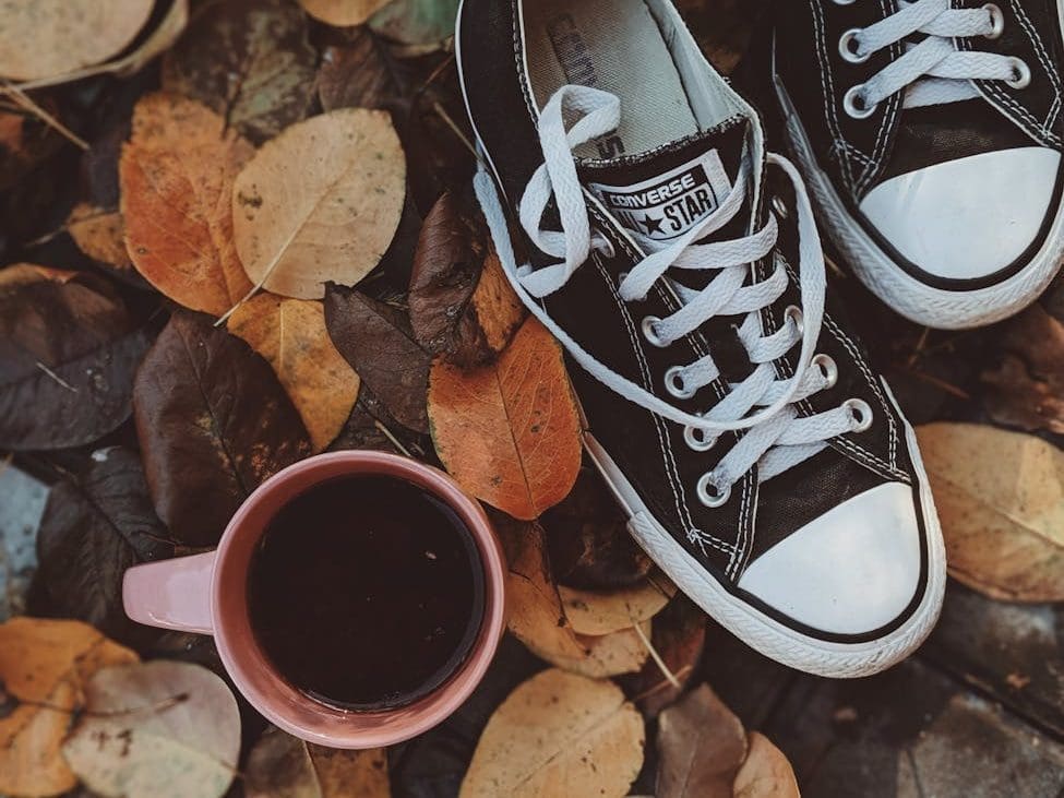 high angle photo of converse all star sneakers near cup of coffee