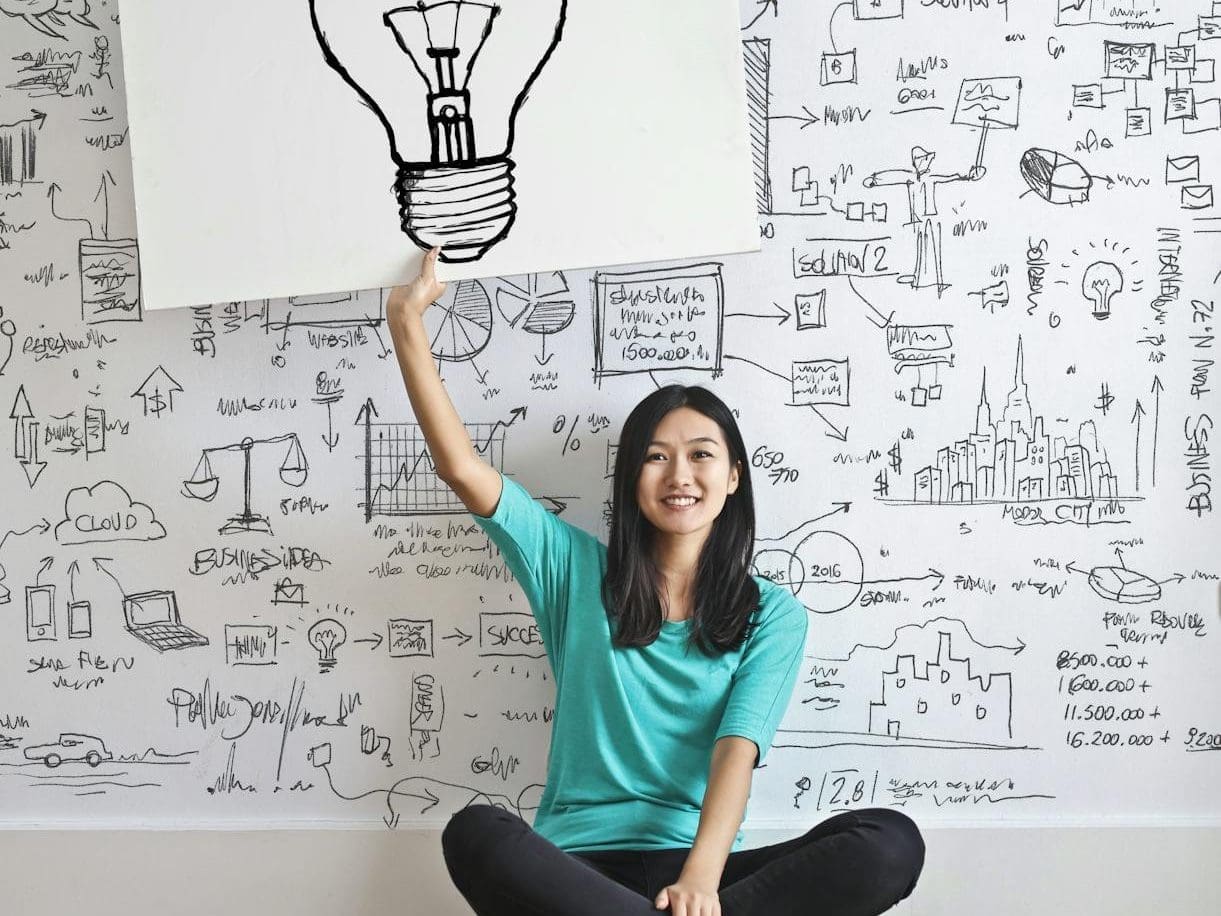 woman draw a light bulb in white board