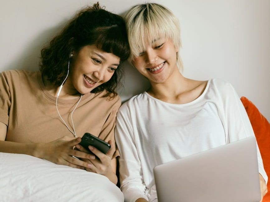 cheerful women using smartphone and laptop