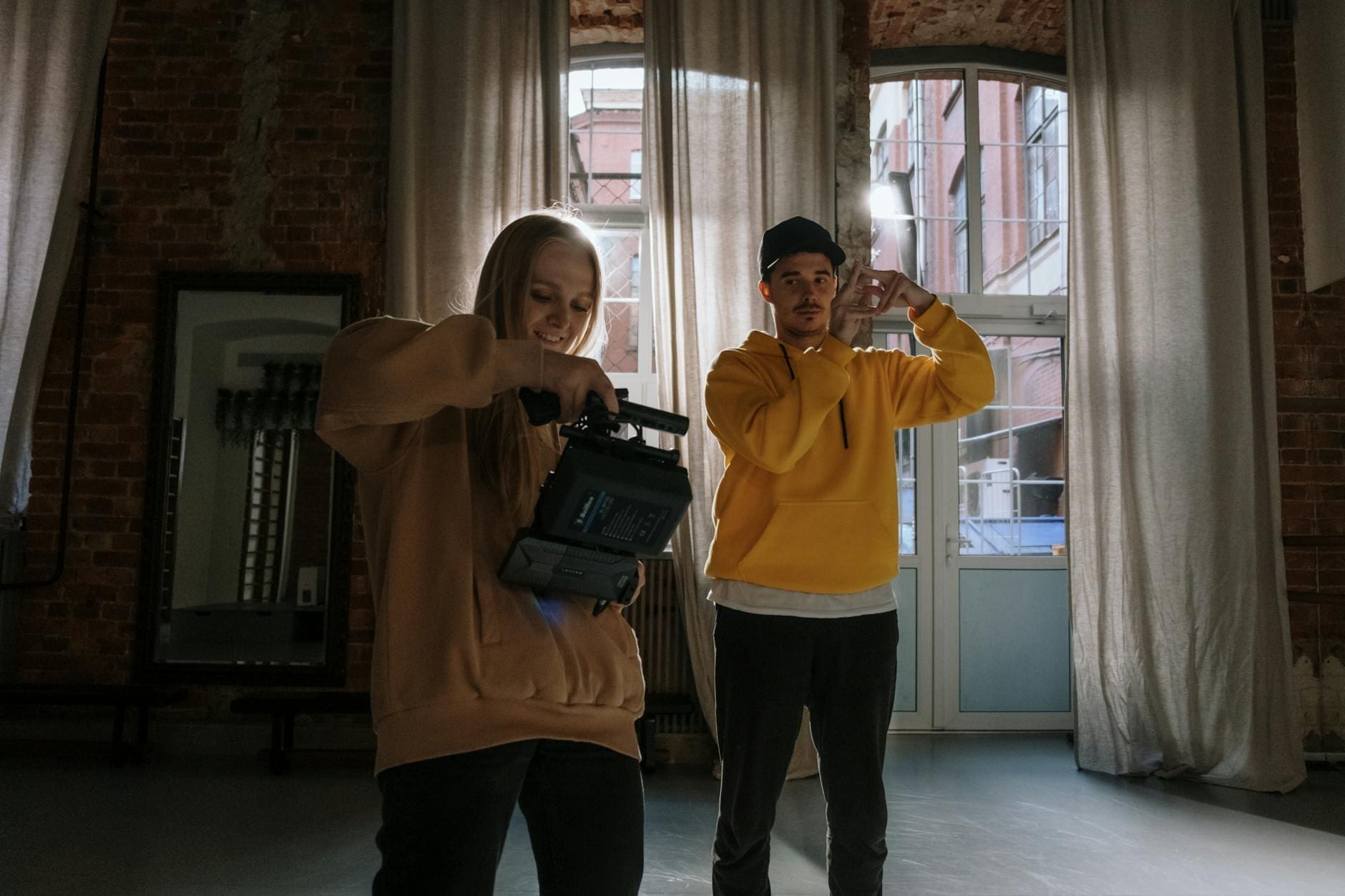 a man and woman wearing sweater while holding a video camera