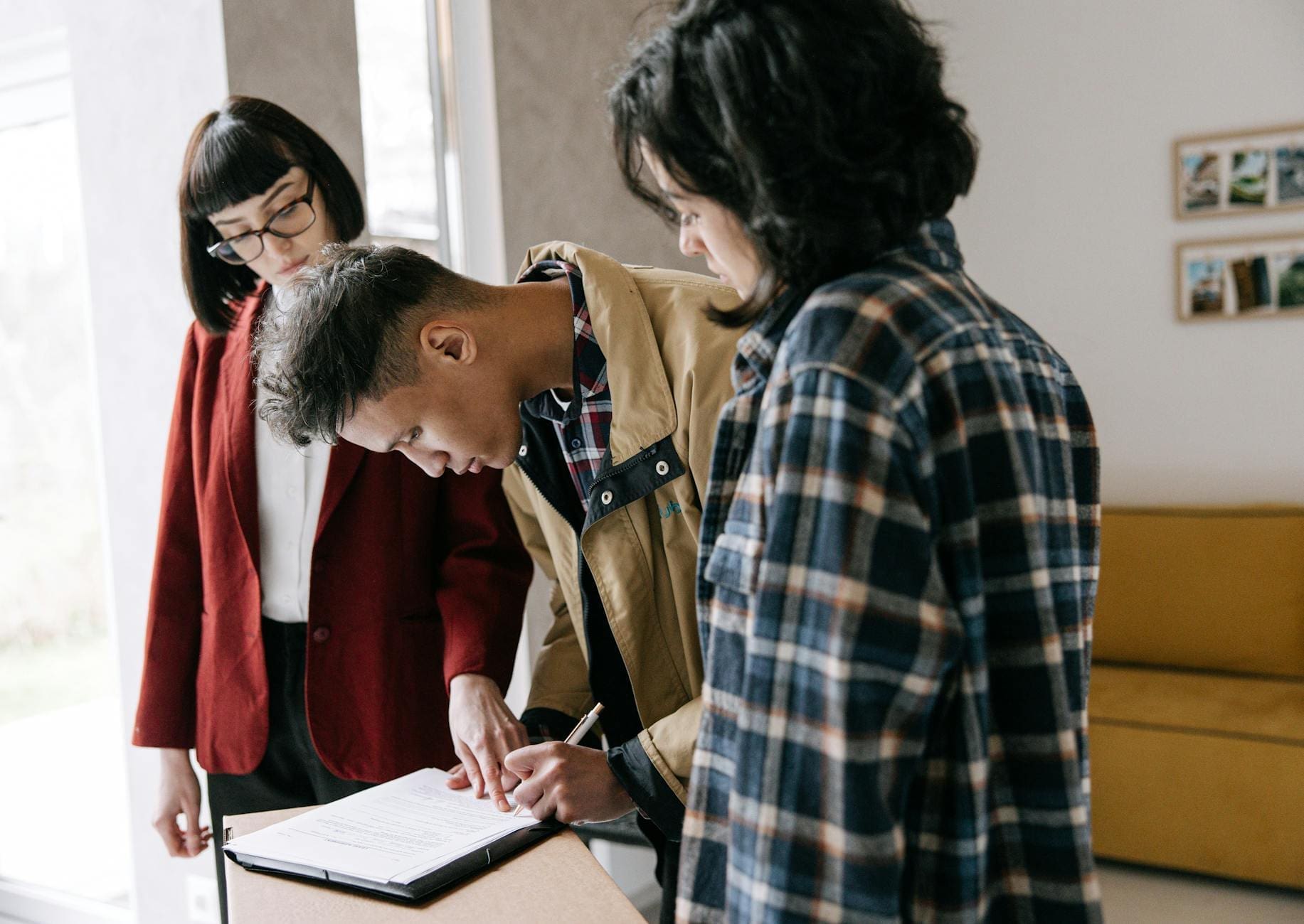 man signing documents beside woman and real estate agent