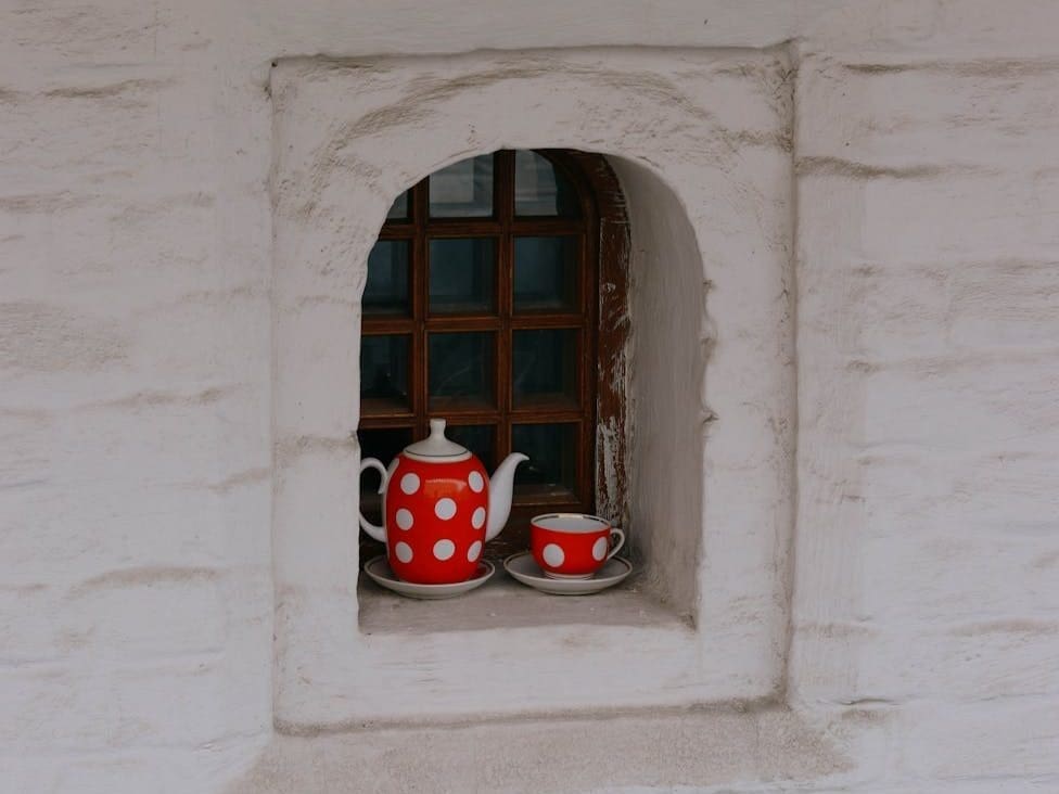 a kettle and a cup by a window