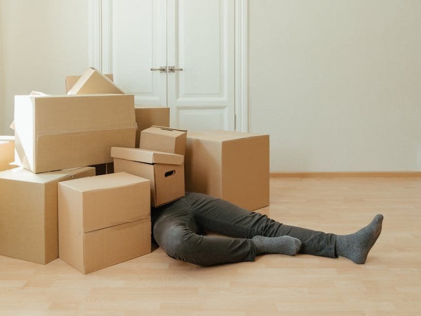 person in black leather boots sitting on brown cardboard boxes