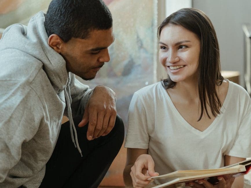 man in gray hoodie sitting beside woman in white shirt