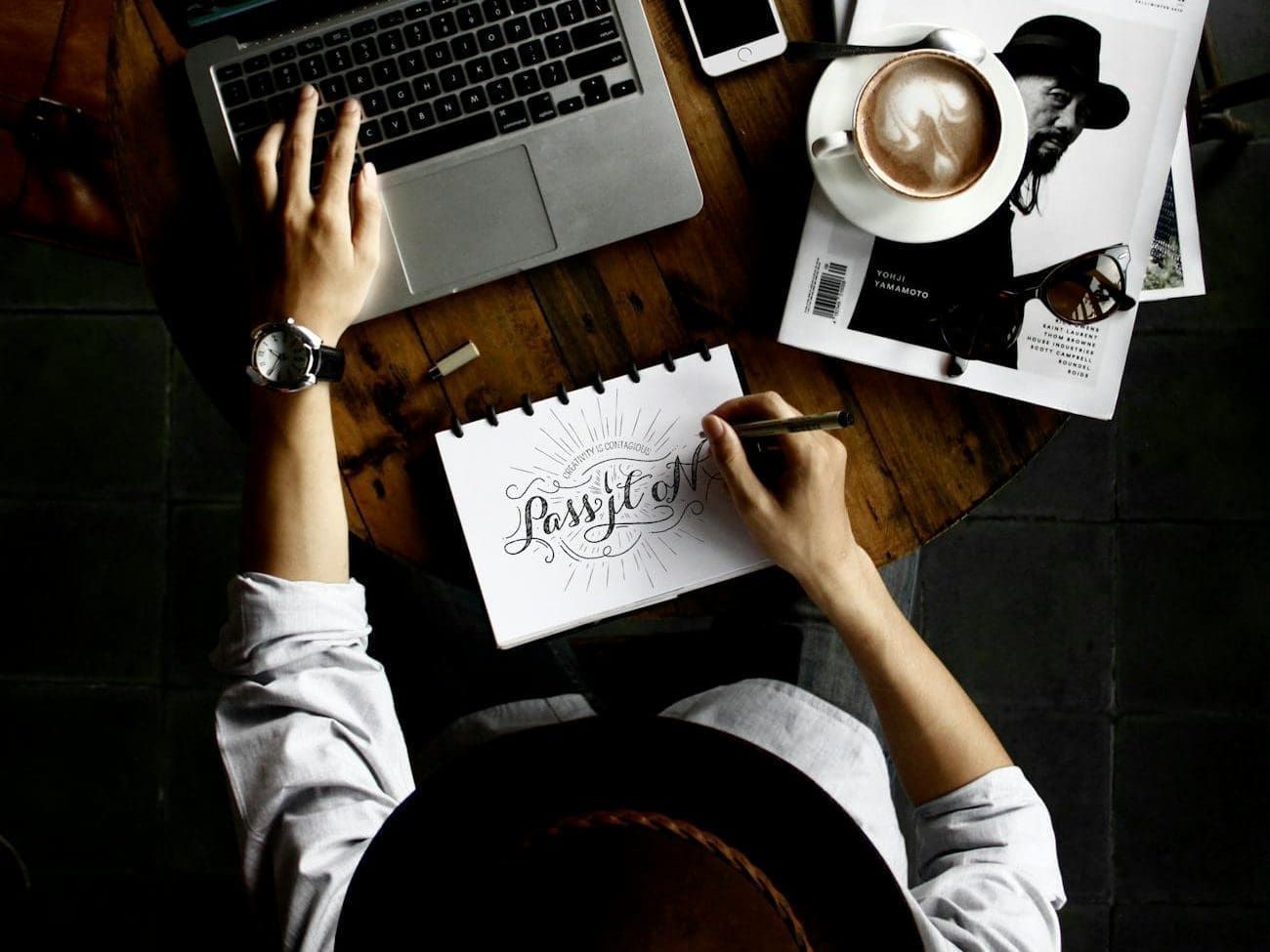 person sitting facing laptop computer with sketch pad