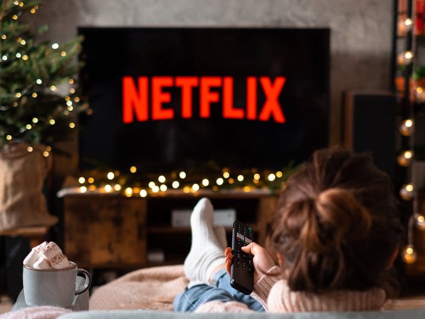 back view of a woman sitting on a sofa and watching television