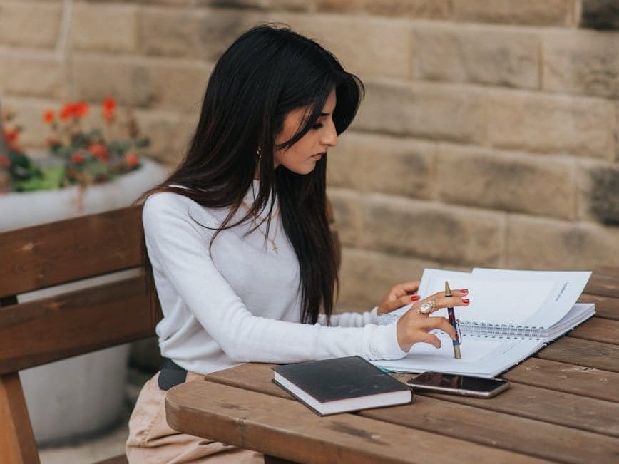 intelligent ethnic worker with notebook at street table