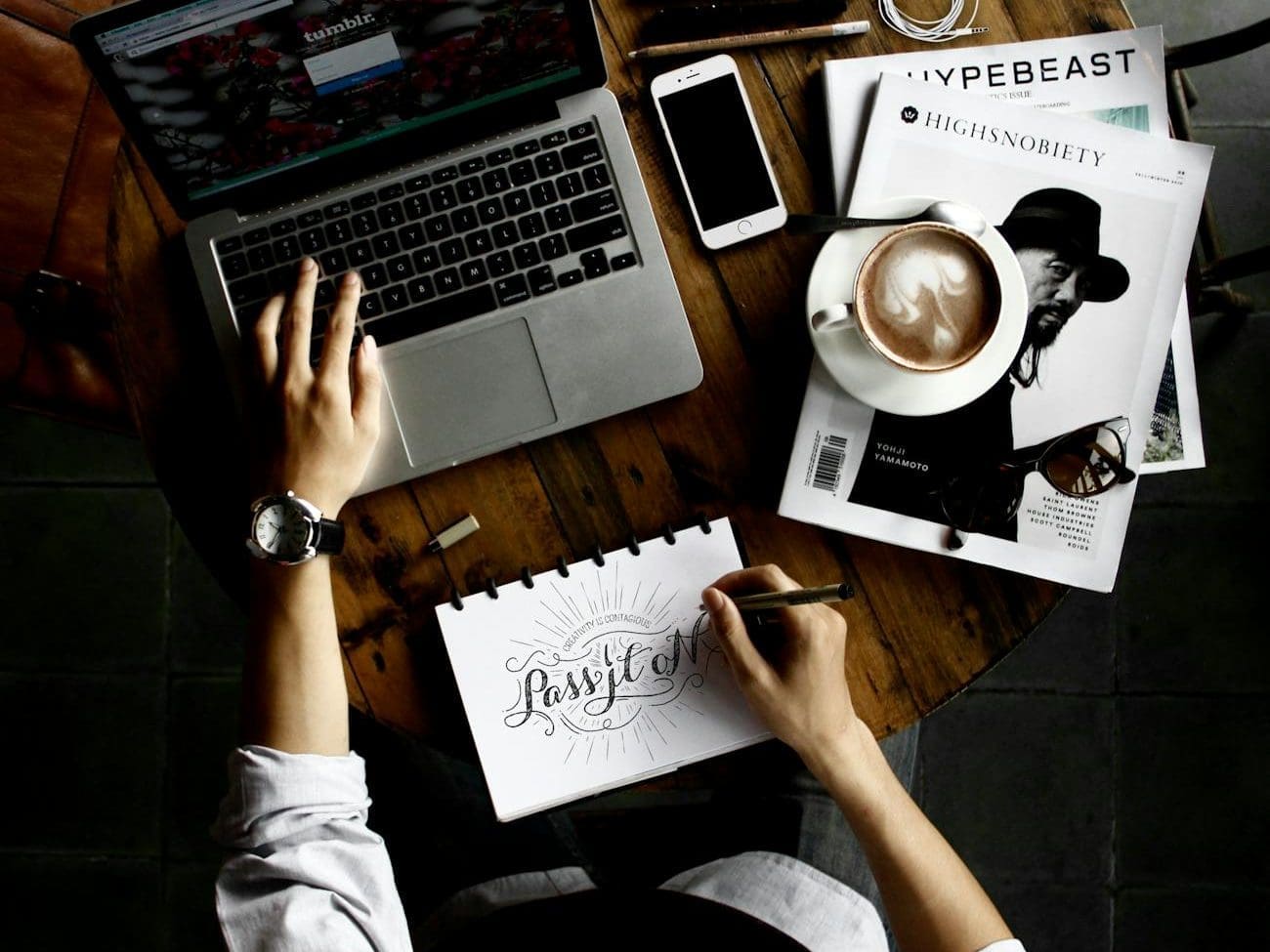 person sitting facing laptop computer with sketch pad