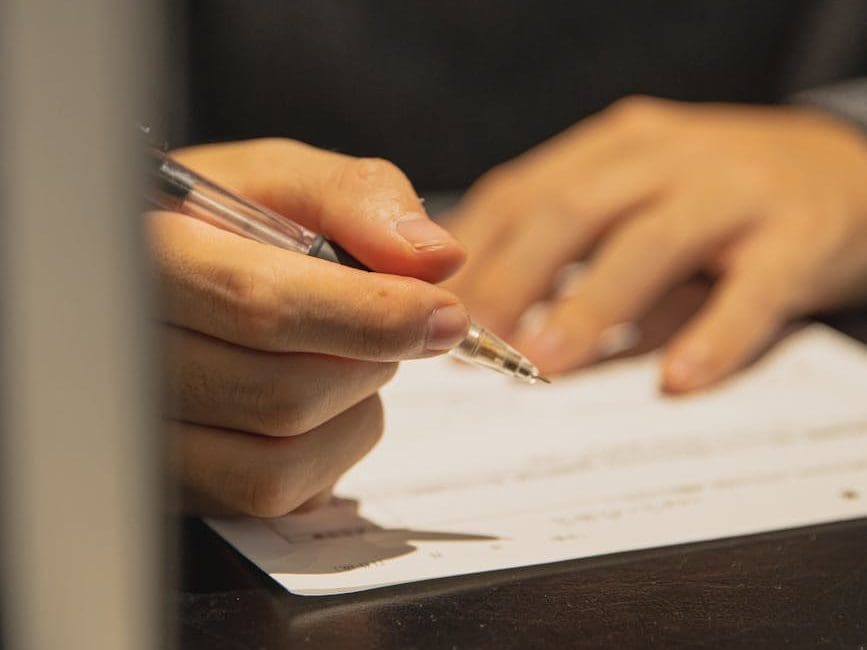 man writing with pen on paper