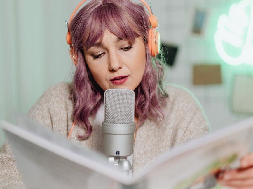 a woman talking on a microphone while reading a book