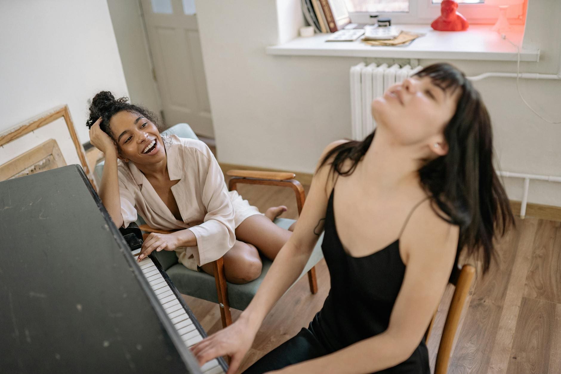 woman in black spaghetti strap dress playing piano