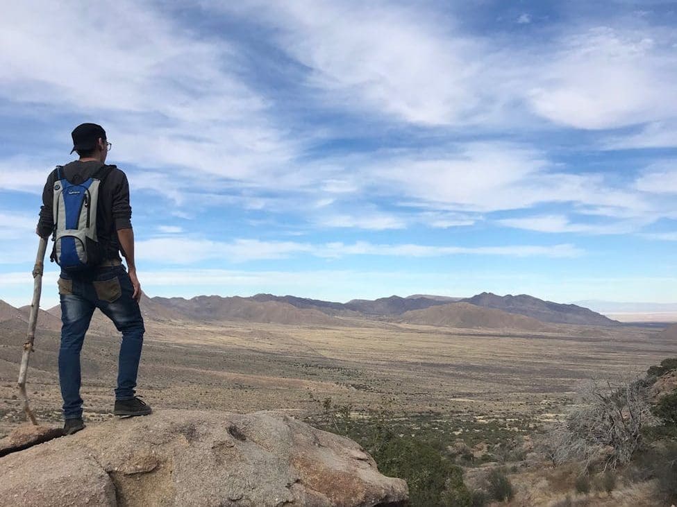 man wearing backpack standing on stone