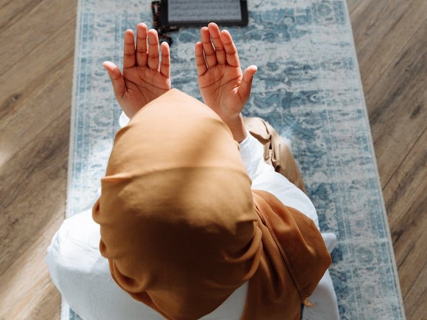 high angle shot of a person kneeling on a blue prayer rug