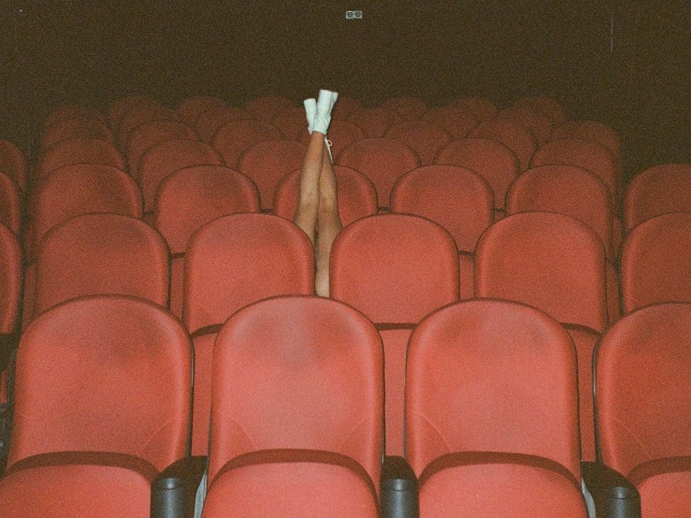 person in white shoes sitting on red chairs