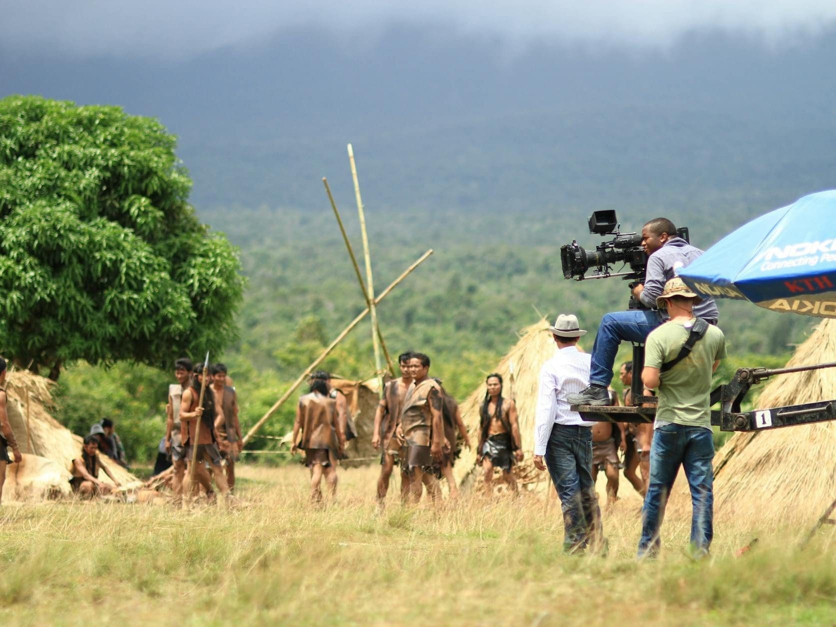 people at the green grass field with the distance holding filming camera during day time