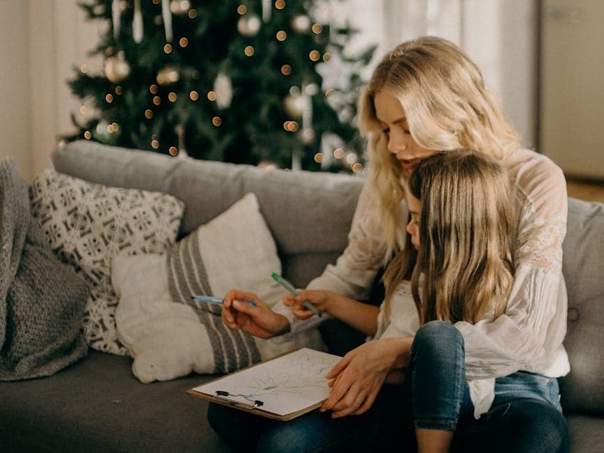 girl sitting on woman s lap while holding pen and paper