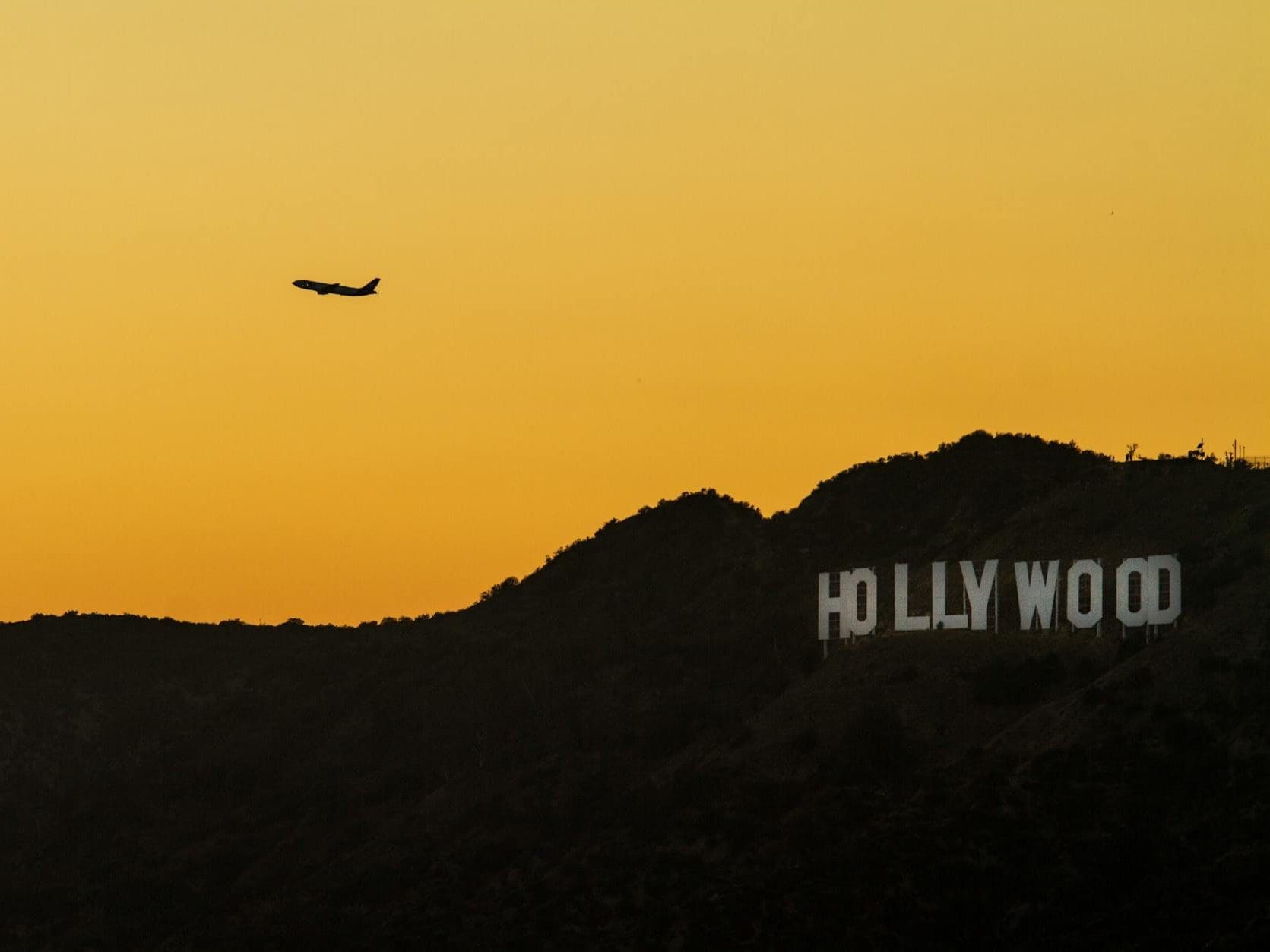 airplane over hollywood sign at sunset